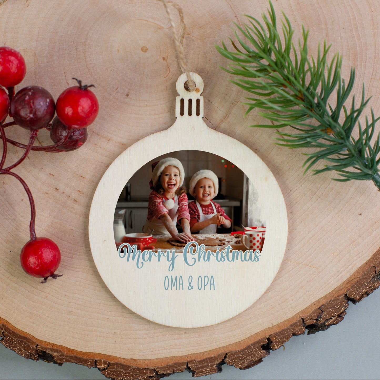 Holz-Weihnachtsanhänger mit Foto zweier Kinder und Schriftzug „Merry Christmas Oma & Opa“, dekoriert mit Beeren und Tannenzweig.
