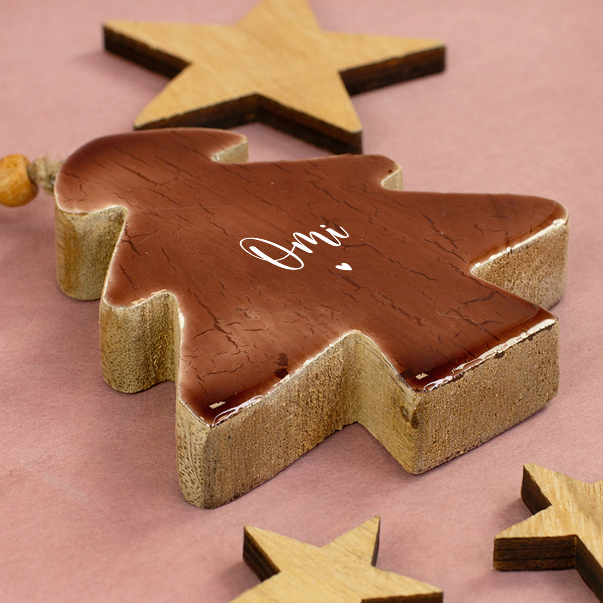 Personalisierter Holz-Tannenbaum mit Aufdruck Omi und Herz liegend zwischen dekorativen Holzsternen