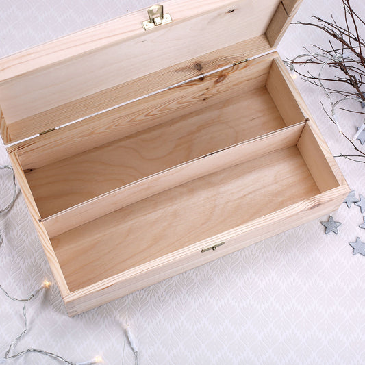 Geöffnete Holzbox mit Einsatz und Messingverschluss auf hellem Hintergrund, dekoriert mit Lichterkette und Sternen