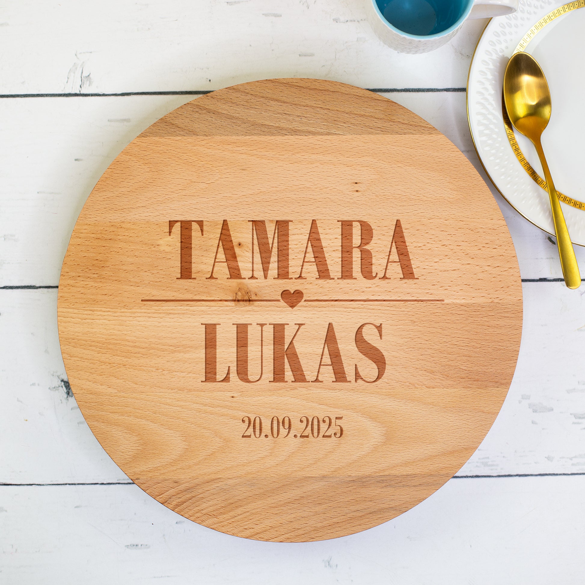 Personalisierte Tortenplatte aus Buchenholz mit gravierten Namen und Datum auf hellem Tisch