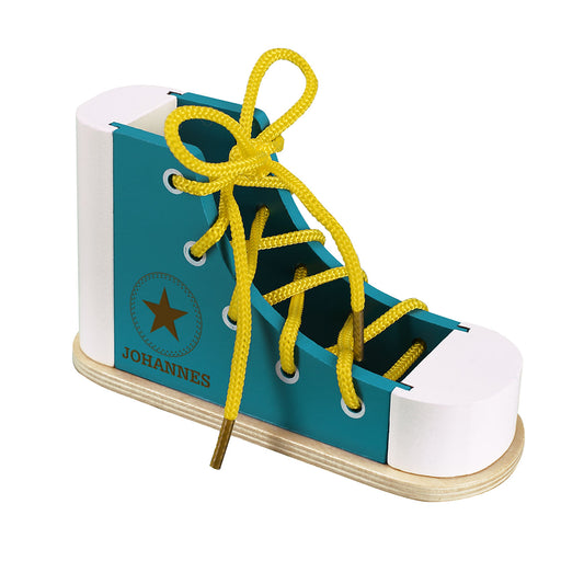 Lernschuh zum Schleife binden aus Holz mit Namensgravur in blau freigestellt auf weißem Hintergrund