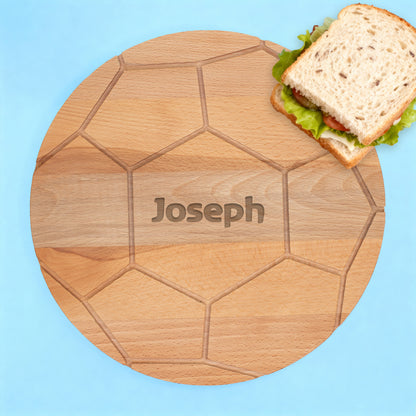 Rundes Buchenholzbrett mit Fußballmuster und graviertem Namen Joseph auf blauem Hintergrund