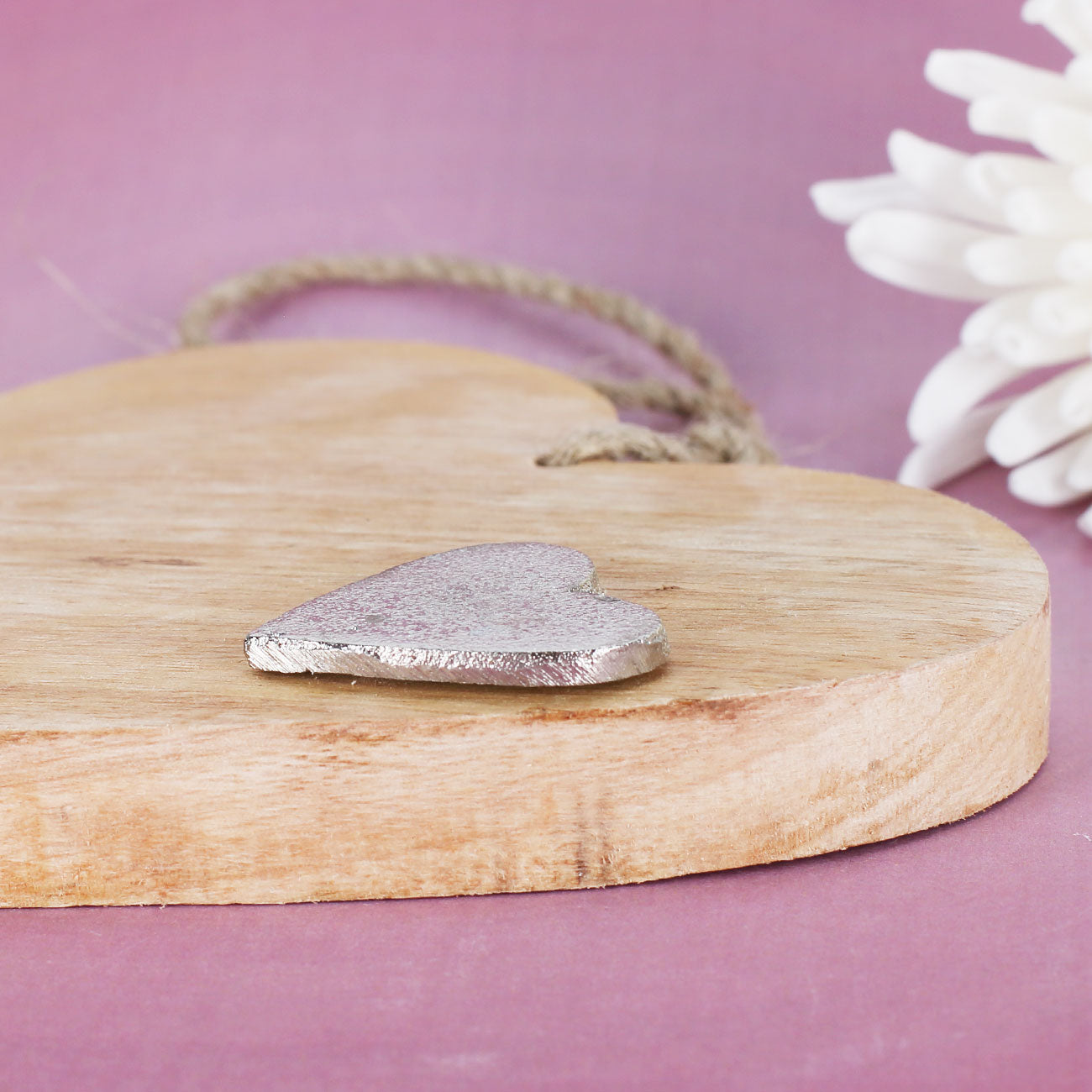 Detailansicht vom Holzherz mit silberfarbenem Metallherz und natürlicher Holzstruktur