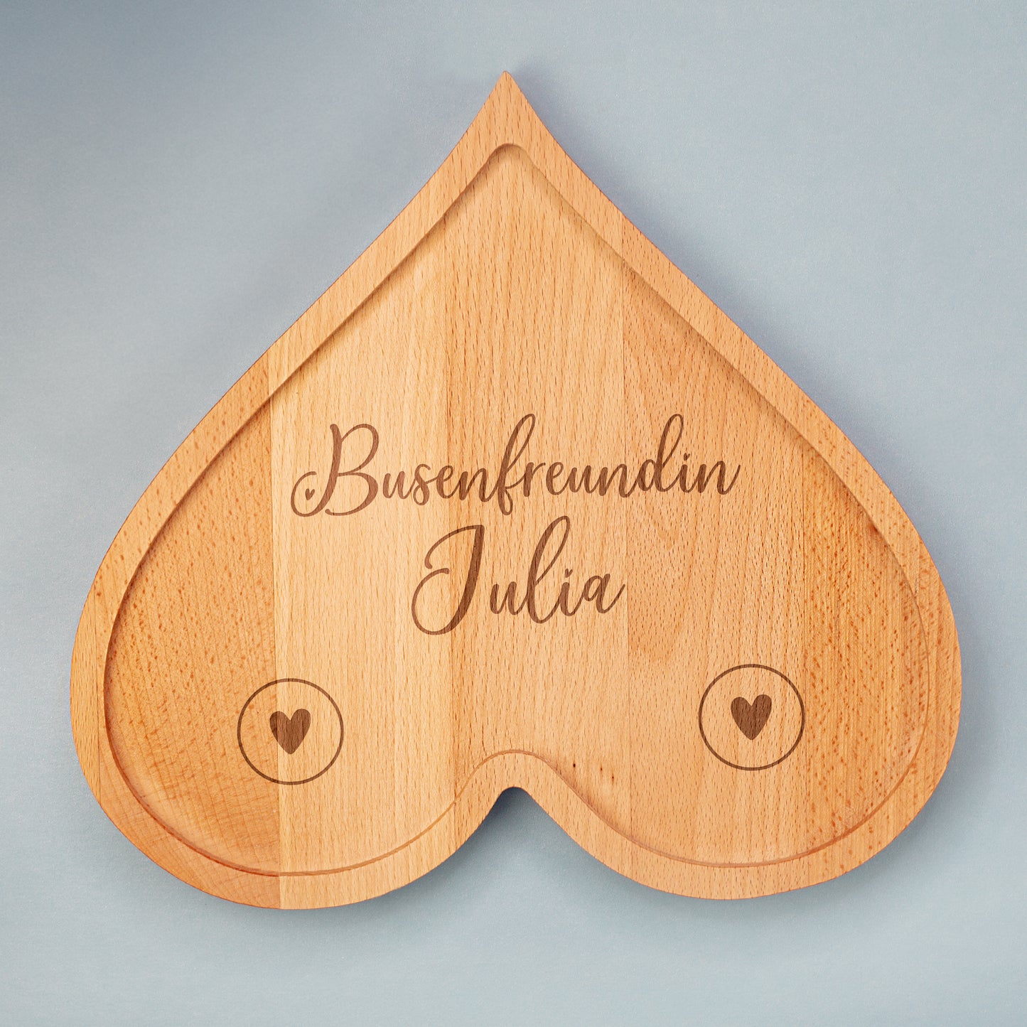 Personalisiertes Frühstücksbrettchen aus Holz in Herzform mit Gravur „Busenfreundin Julia“ auf hellem Hintergrund