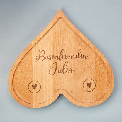 Personalisiertes Frühstücksbrettchen aus Holz in Herzform mit Gravur „Busenfreundin Julia“ auf hellem Hintergrund