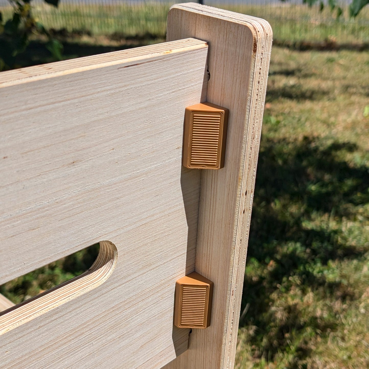 Detailansicht zweier brauner Halteelemente, die das Rückenteil der Holzbank fixieren