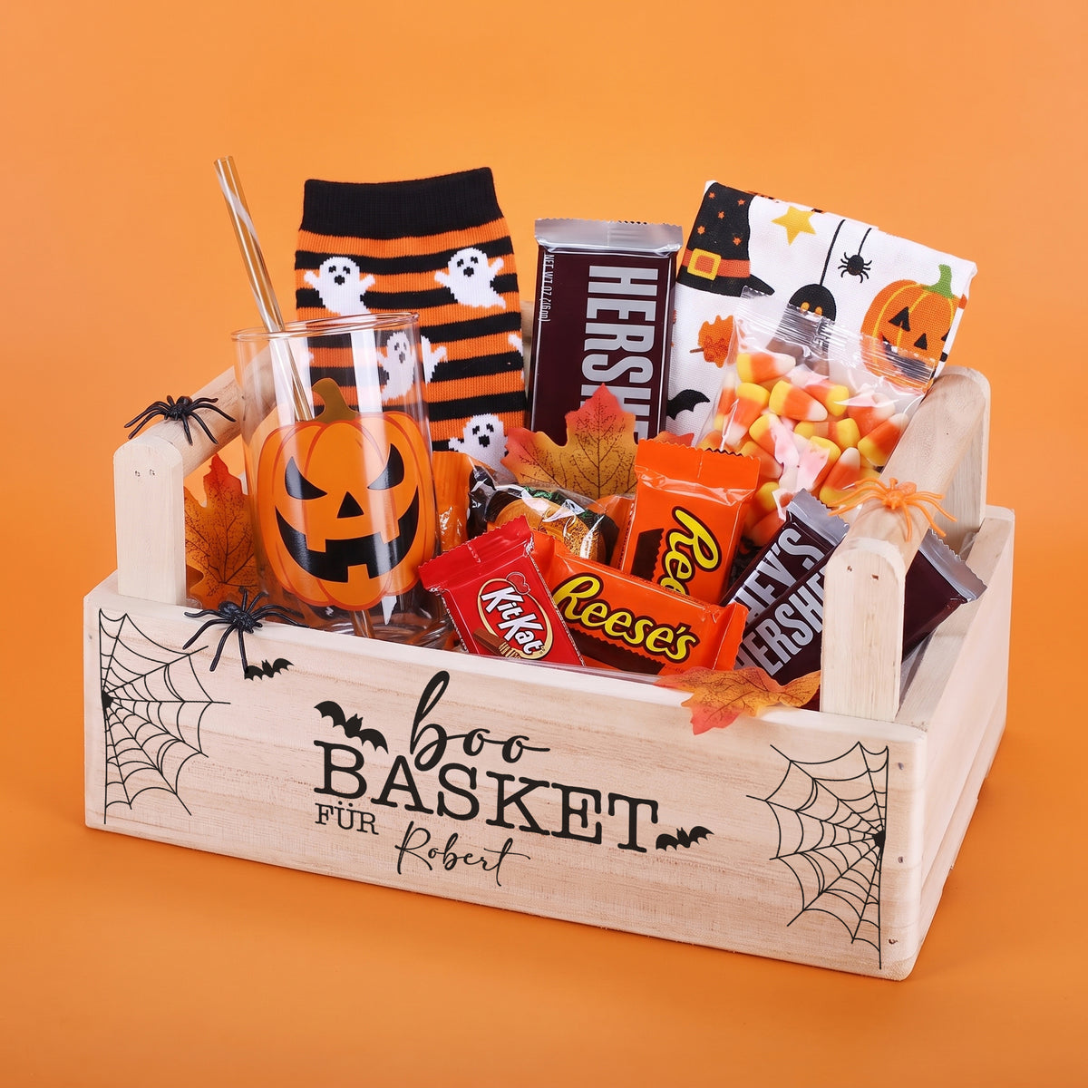 Personalisierter Halloween Geschenkkorb aus Holz mit Name und Süßigkeiten auf orangem Hintergrund