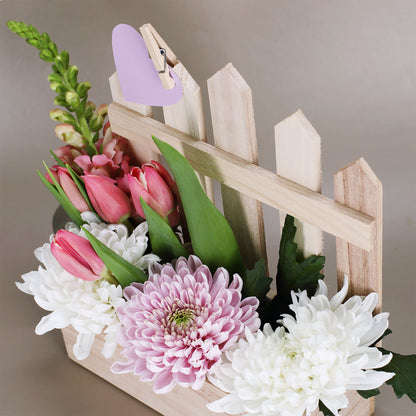 Detailansicht Pflanzkorb aus Holz mit Zaun als Rankhilfe, gefüllt mit Frühlingsblumen und Dekoration