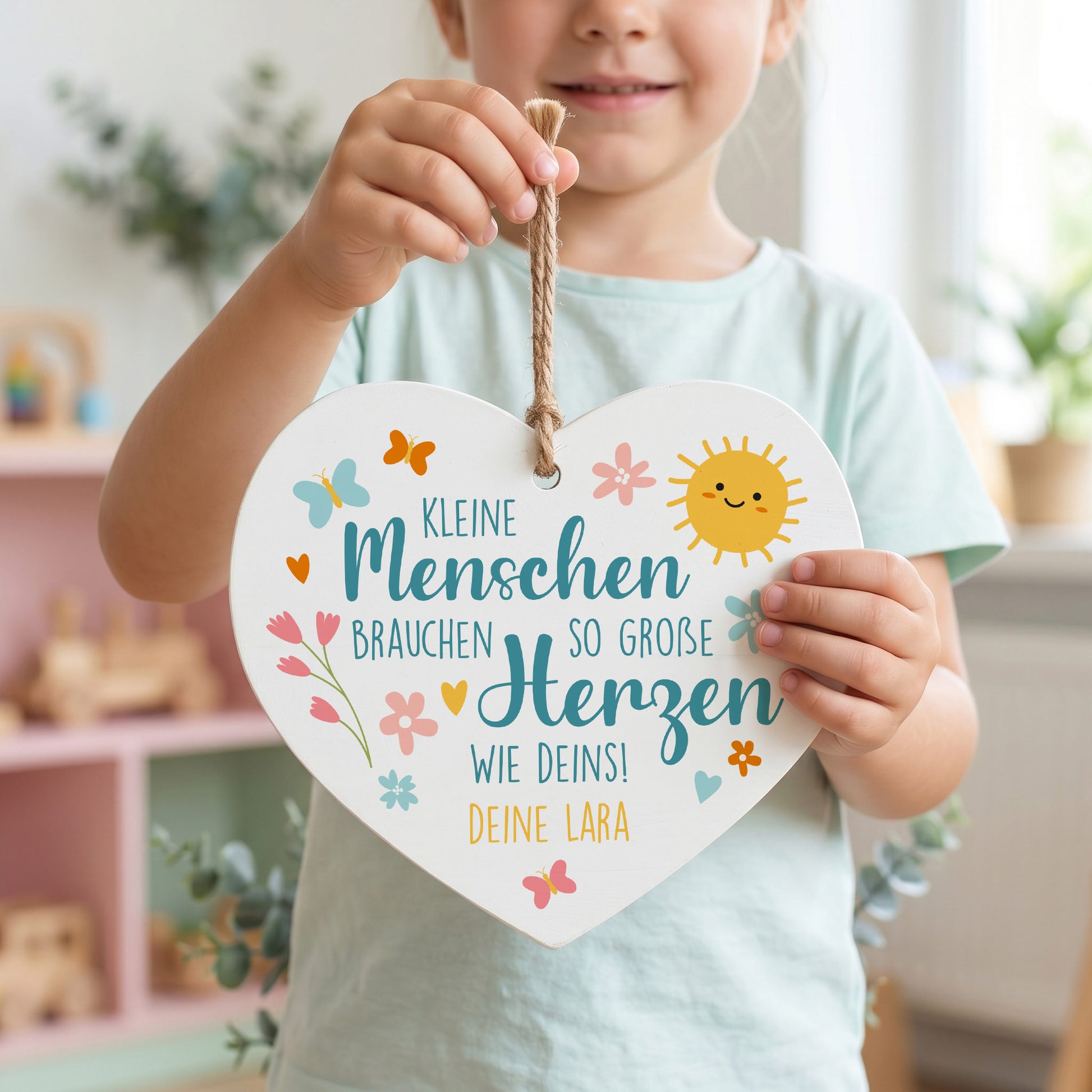 Kind hält personalisiertes Holzherz mit buntem Erzieherin Spruch und Wunschtext Deine Lara