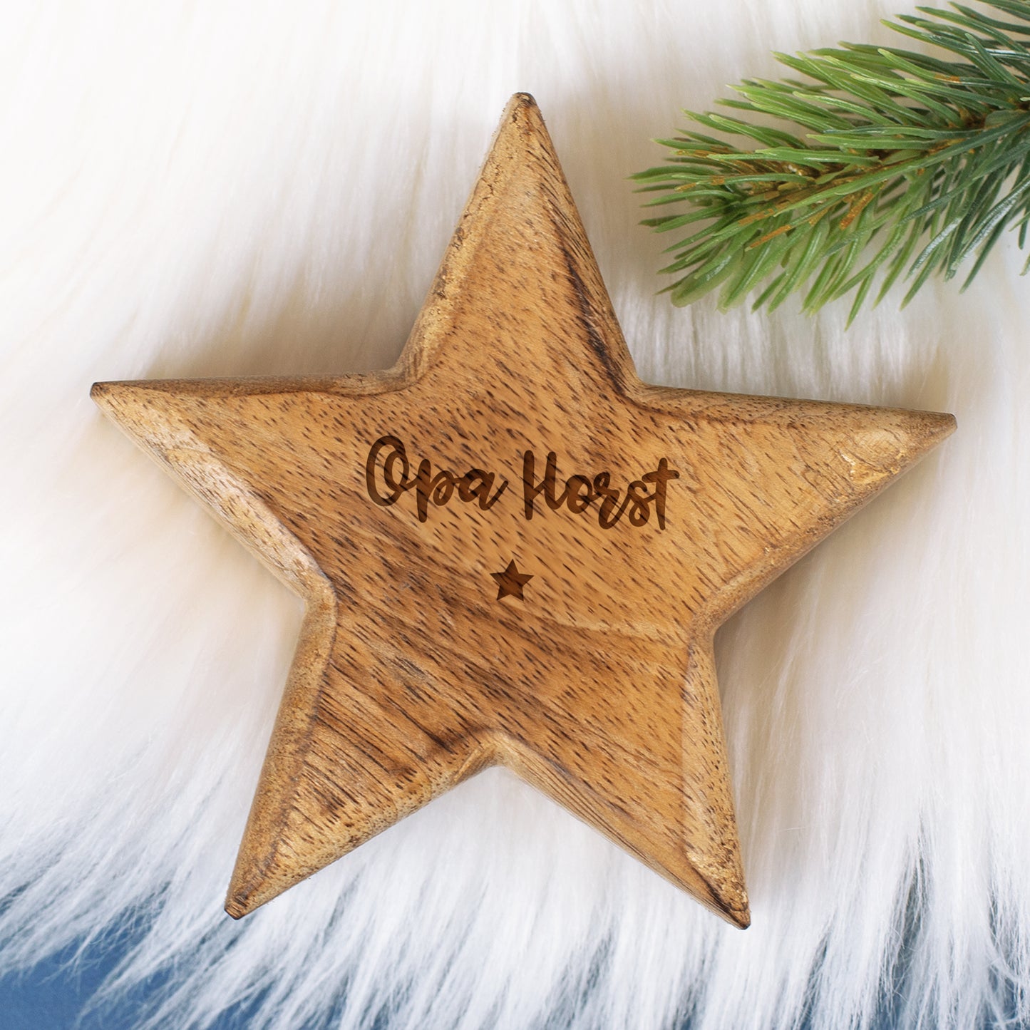Personalisierter Holzstern mit Gravur „Opa Horst“ auf weißem Fell und Tannenzweig