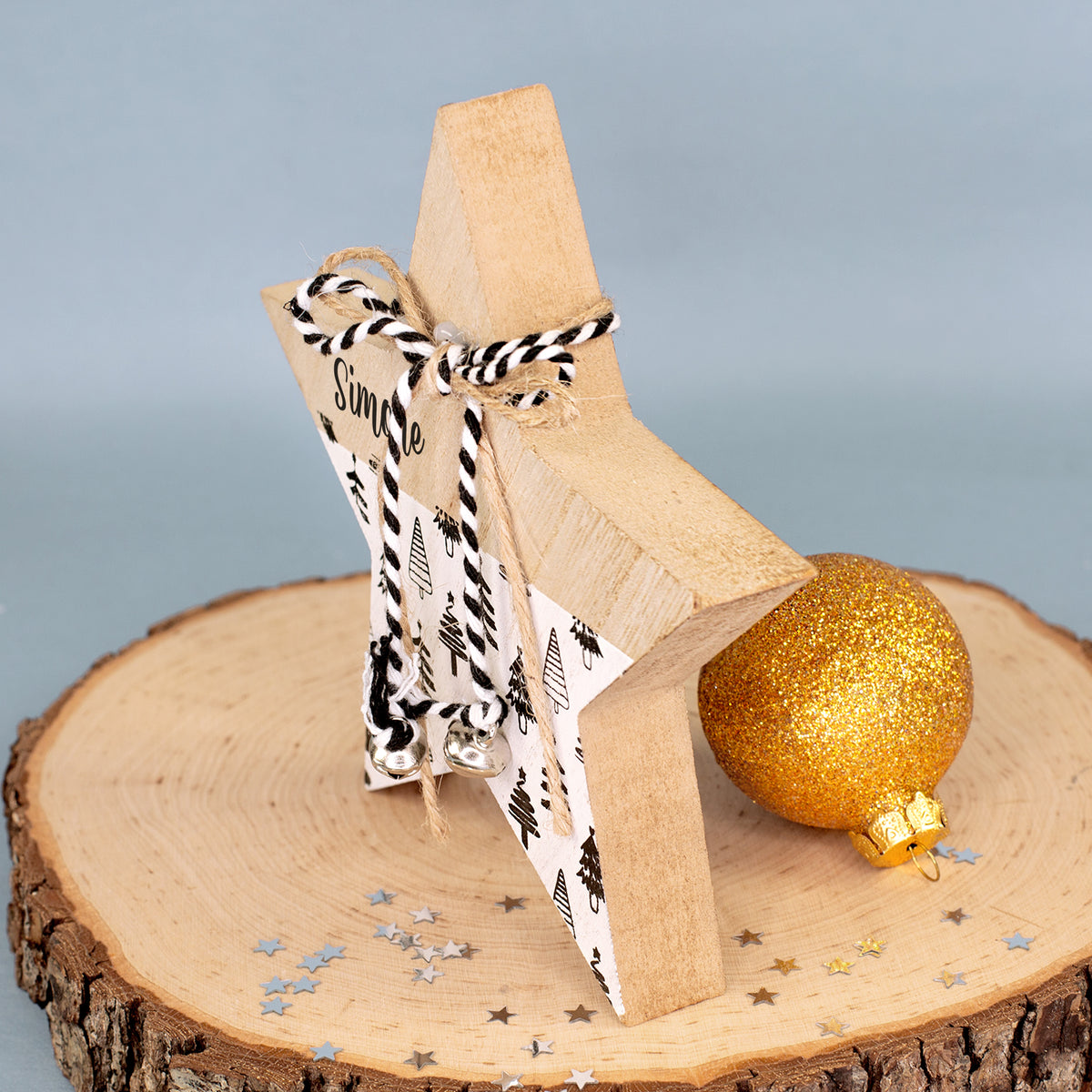 Seitenansicht des personalisierten Holzsterns mit Schnüren, kleinen silberfarbenen Glöckchen und Weihnachtskugel