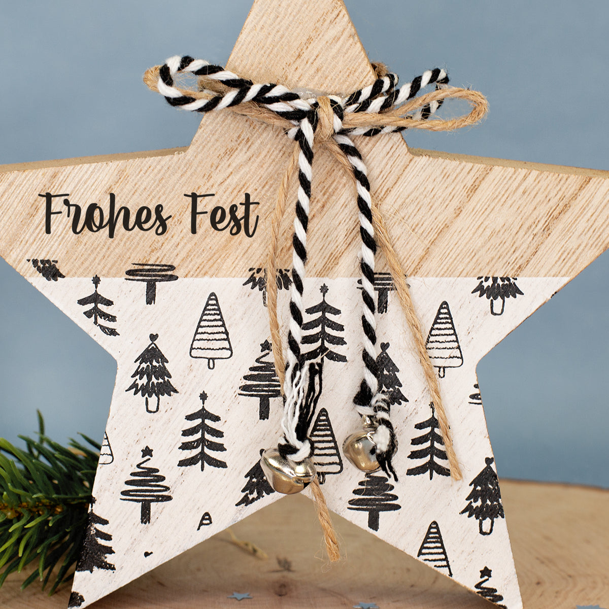 Nahaufnahme des Holzsterns mit Wunschtext „Frohes Fest“, Tannenbaum-Muster, Schleife und kleinen Glöckchen