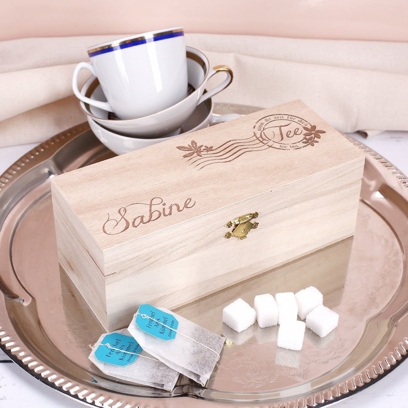 Teebox aus Holz mit Gravur „Sabine“, dekorativ auf einem Silbertablett mit Zuckerwürfeln und Teebeuteln