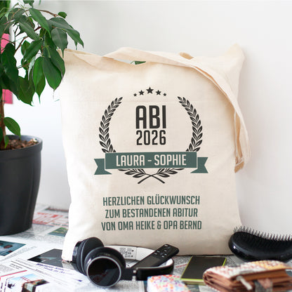 Gefüllter Beutel zum Abitur mit persönlichem Aufdruck stehend an eine Wand gelehnt