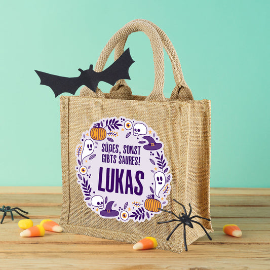Halloween-Jutebeutel mit personalisiertem Namen und Süßigkeiten-Deko auf hellem Hintergrund.