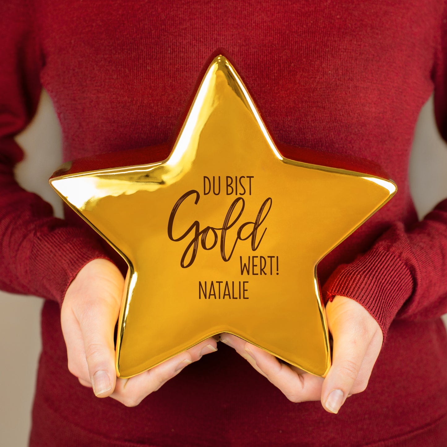 Goldfarbener Keramikstern von Leonardo mit Motiv „Du bist Gold wert!“ und personalisiertem Namen – in der Hand