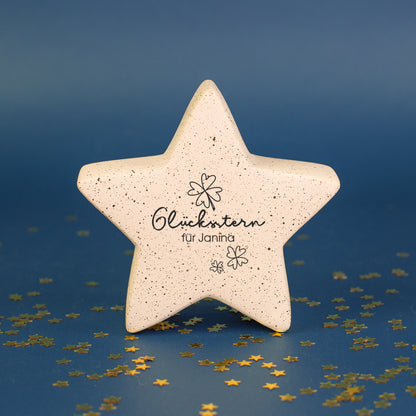 Kleiner Glücksstern aus Keramik mit Personalisierung vor blauem Hintergrund