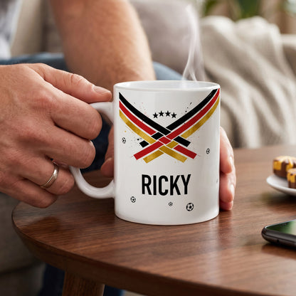 Weiße Fußballtasse mit Name Ricky, dampfendem Getränk, schwarz-rot-goldenem Motiv und kleinen Fußball-Elementen