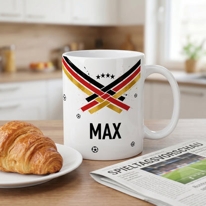 Fußball Tasse mit Name Max auf Küchentisch, Fan-Motiv in Schwarz Rot Gold, Croissant und Zeitung im Hintergrund