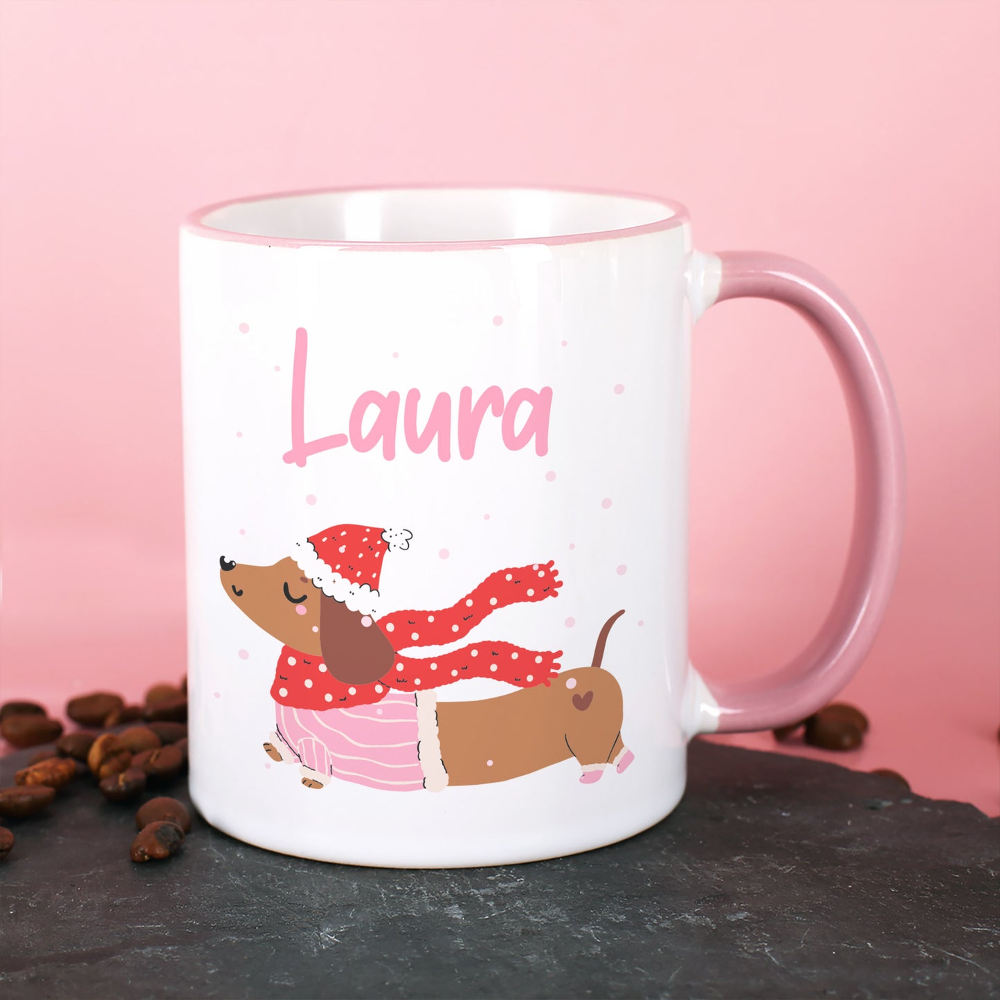 Weiße Tasse mit Dackel im Winteroutfit und personalisiertem Namen, rosa Hintergrund