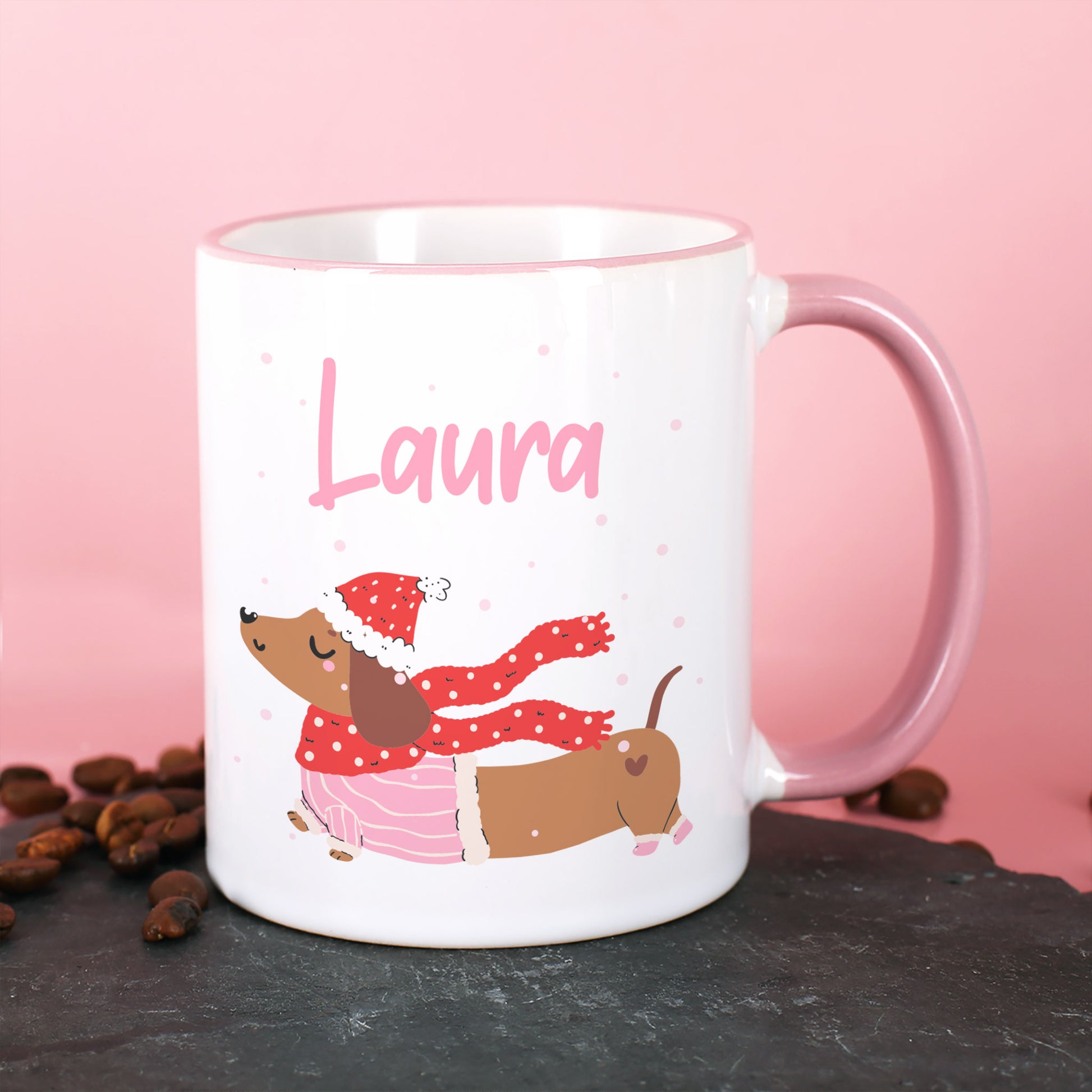 Weiße Tasse mit Dackel im Winteroutfit und personalisiertem Namen, rosa Hintergrund