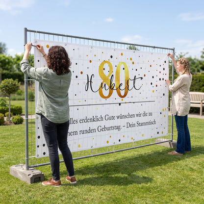 Bauzaun Banner zum 80. Geburtstag mit Name Hubert und Wunschtext wird draußen befestigt