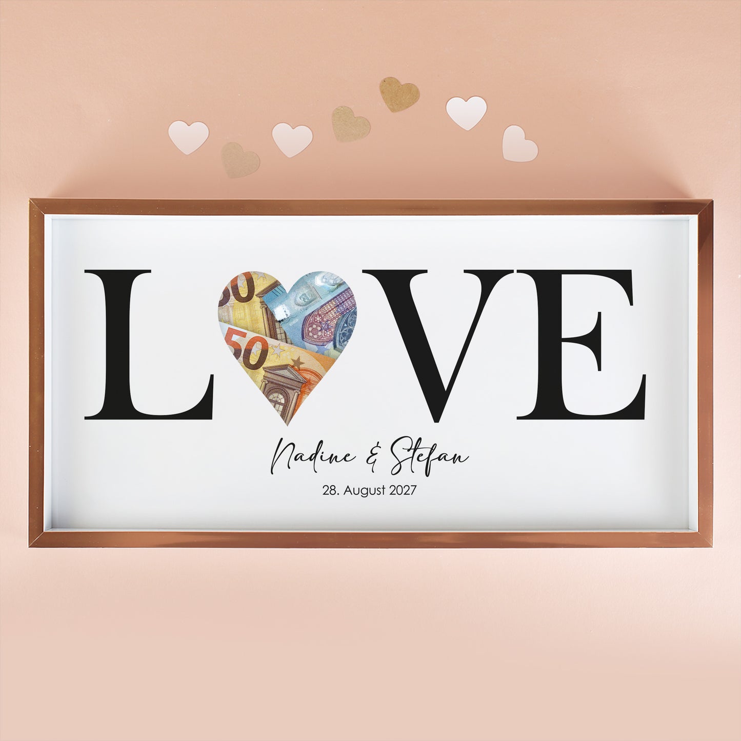 Geldgeschenk Bilderrahmen mit LOVE Motiv, Namen Nadine und Stefan, Datum und Euro-Scheinen in der Herzöffnung vor rosa Hintergrund