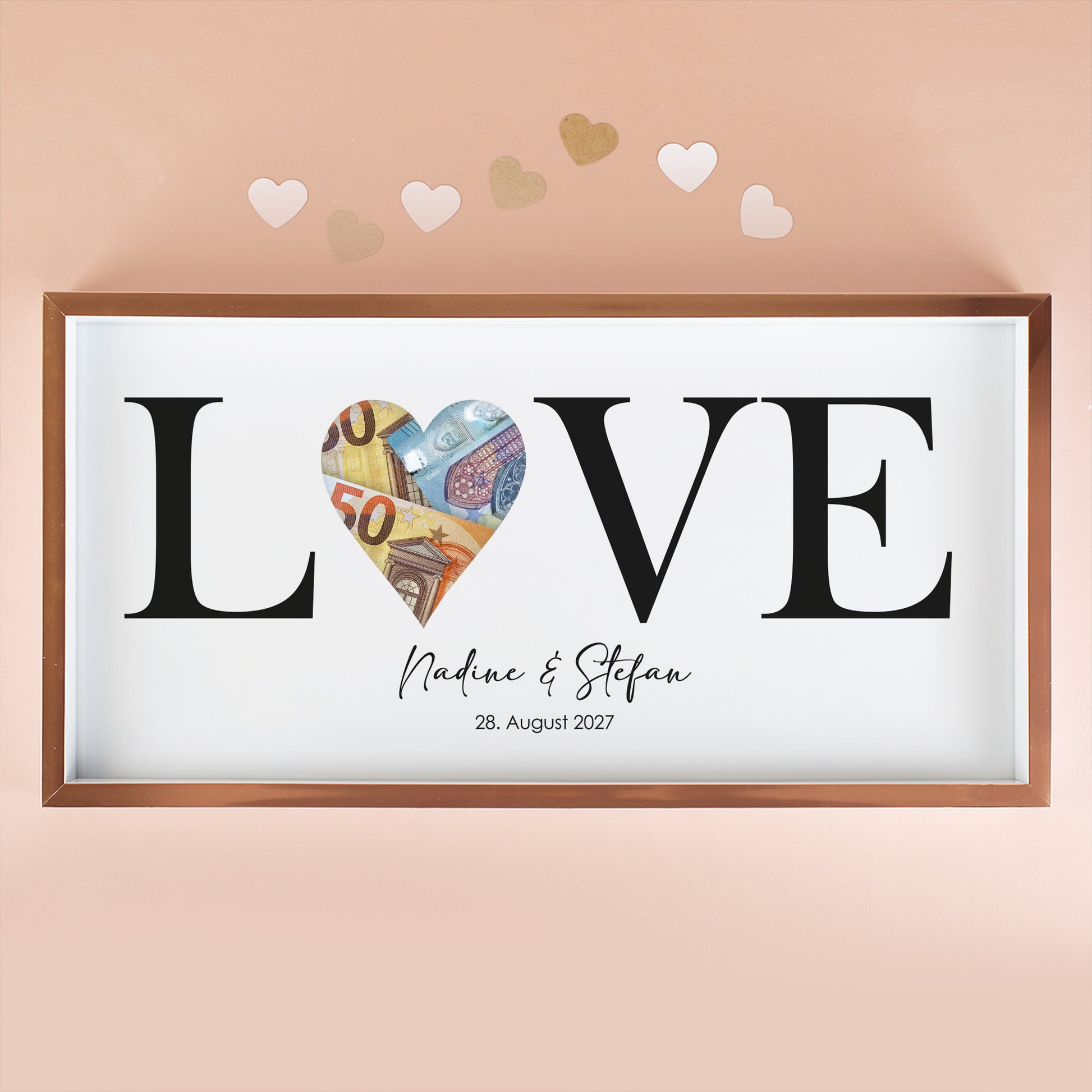 Geldgeschenk Bilderrahmen mit LOVE Motiv, Namen Nadine und Stefan, Datum und Euro-Scheinen in der Herzöffnung vor rosa Hintergrund