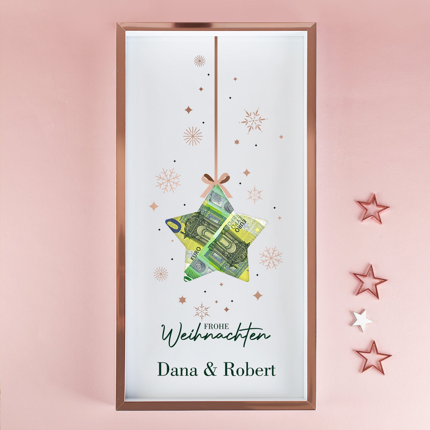 Geldgeschenk Bilderrahmen zu Weihnachten mit Namen Dana und Robert, Stern-Aussparung und Euro-Scheinen vor rosa Wand
