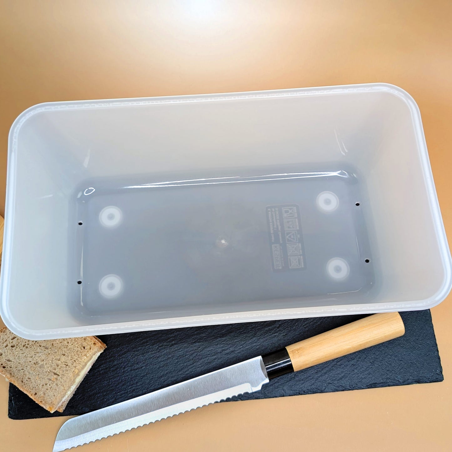 Blick in den Brotkasten von oben mit Messer und Brot auf Schneidebrett