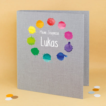 Zeugnismappe aus Leinen in Grau mit buntem Farbkleckse-Motiv und Name Lukas bedruckt