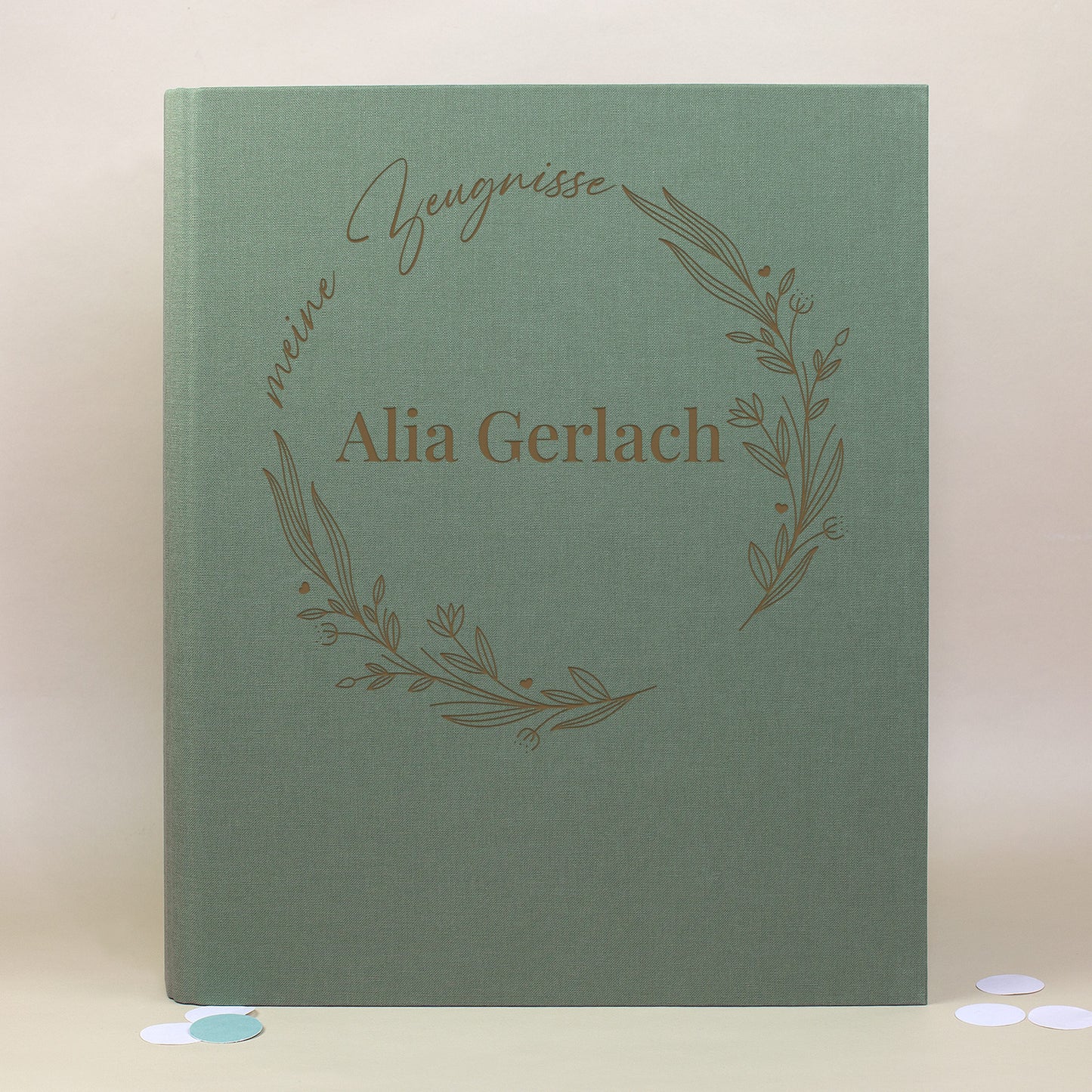 Grüne Zeugnismappe aus Leinen mit floralen Illustrationen im Ring, Aufdruck „meine Zeugnisse“ und personalisiertem Namen „Alia Gerlach“.