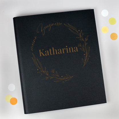 Schwarze Zeugnismappe aus Leinen mit floralen Lineart-Elementen, Aufdruck „meine Zeugnisse“ und personalisiertem Namen „Katharina“.