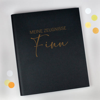 Zeugnismappe aus schwarzem Leinen mit Gravur „Meine Zeugnisse“ und personalisiertem Namen Finn.