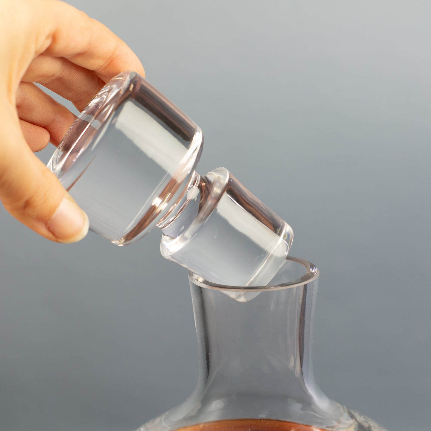 Hand setzt den massiven Glaskorken auf die Karaffe, Detailaufnahme