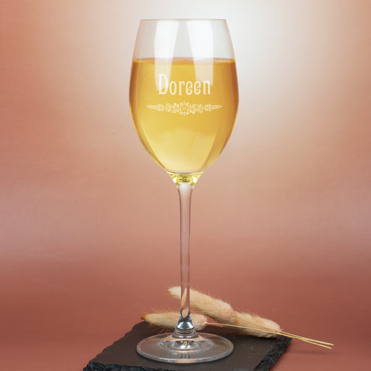 Personalisiertes Leonardo Weißweinglas mit Gravur Doreen und floralem Ornament, auf warmem Hintergrund mit Deko