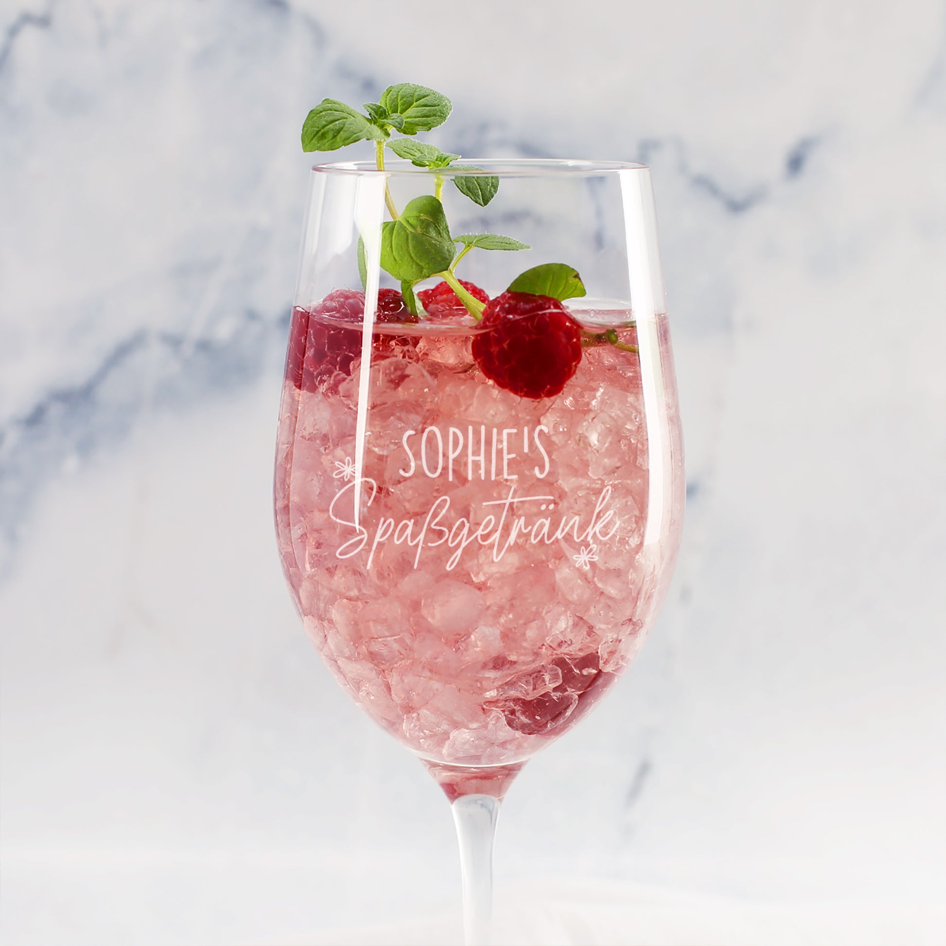 Personalisiertes Weinglas mit Gravur Sophies Spaßgetränk, rosa Drink, Himbeeren und Minze vor hellem Hintergrund