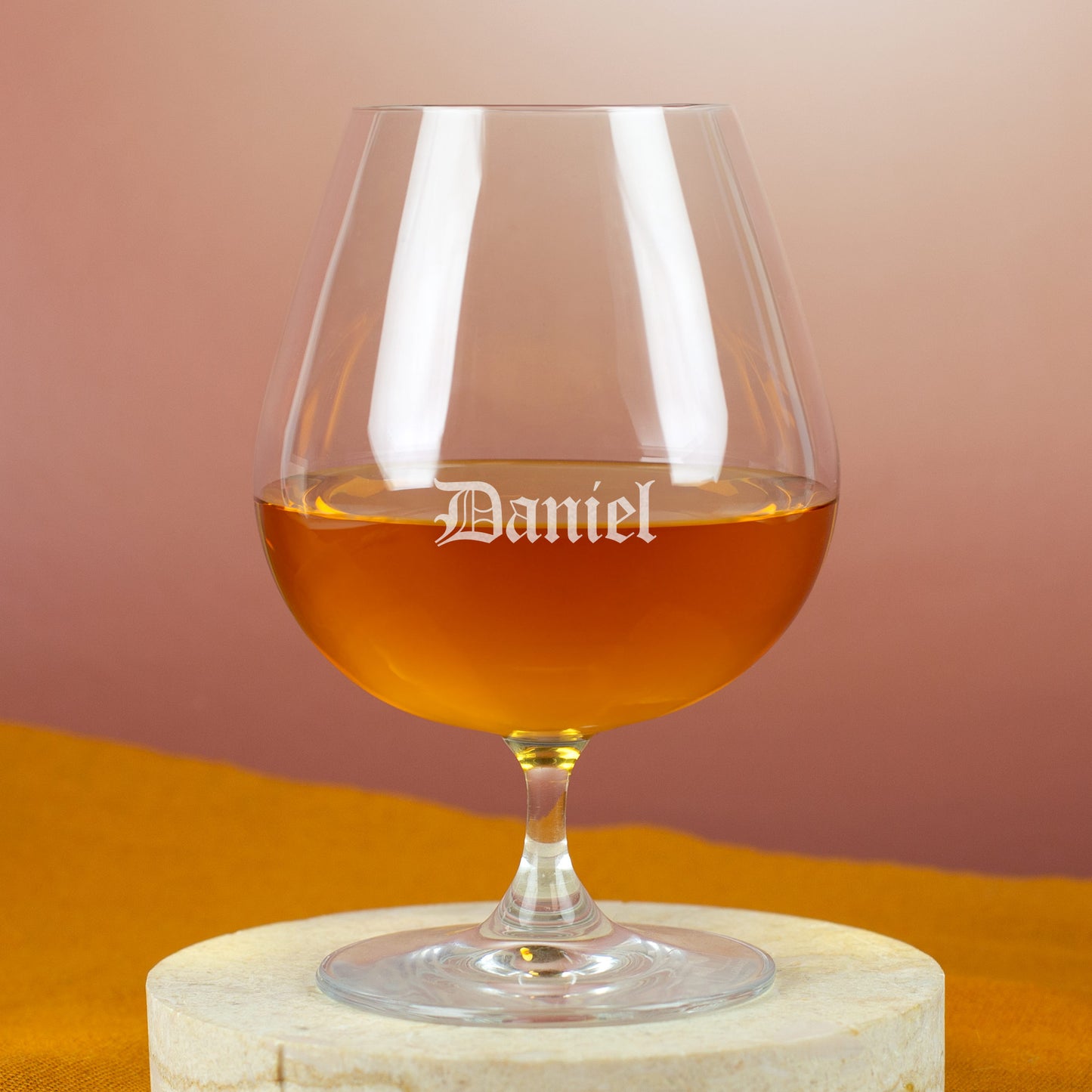 Personalisierter Cognacschwenker mit Gravur „Daniel“ in Frakturschrift – auf hellem Holzuntergrund mit gelbem Tuch.