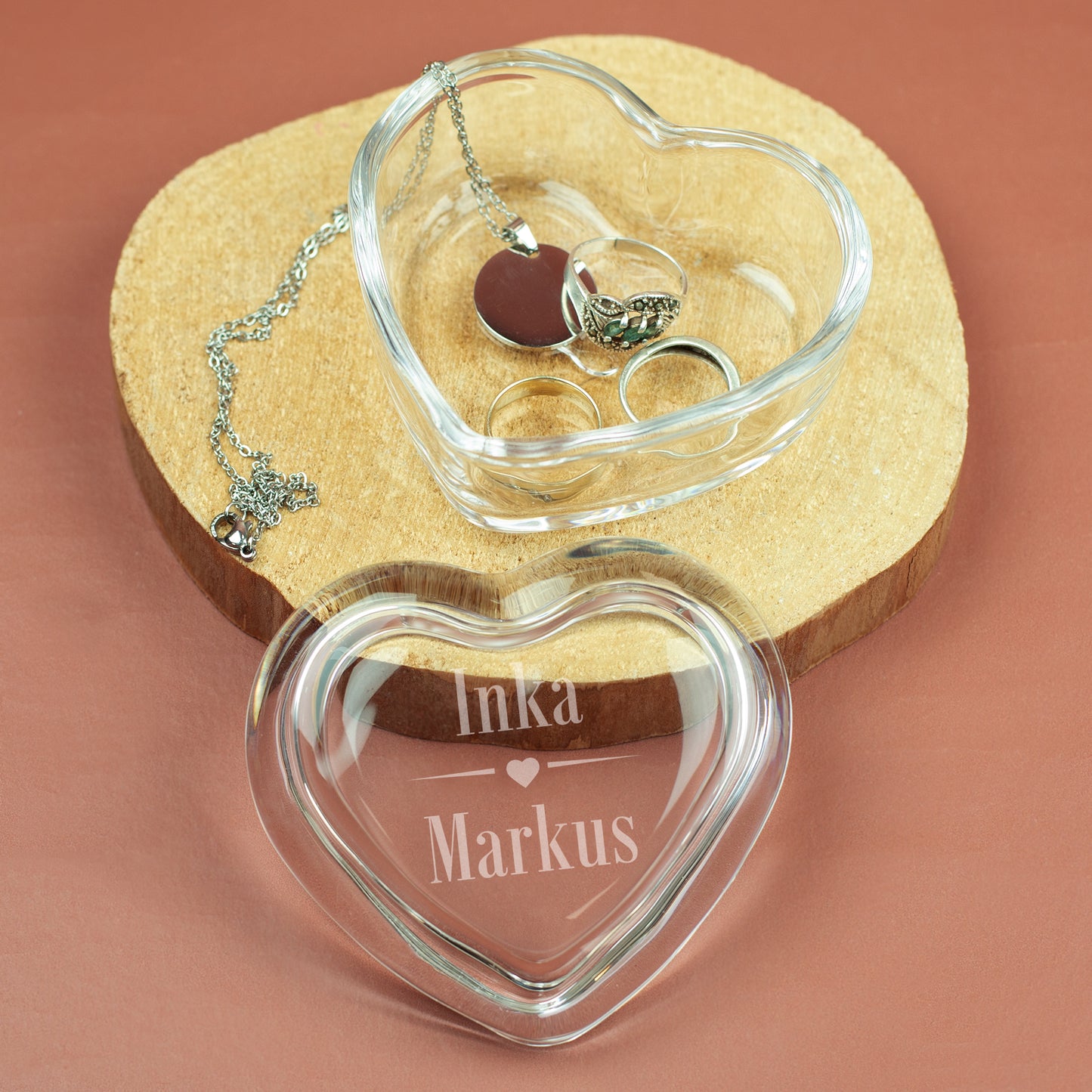 Glasdose in Herzform mit gravierten Namen, geöffnet auf Holzunterlage – Schmuck in der Dose sichtbar