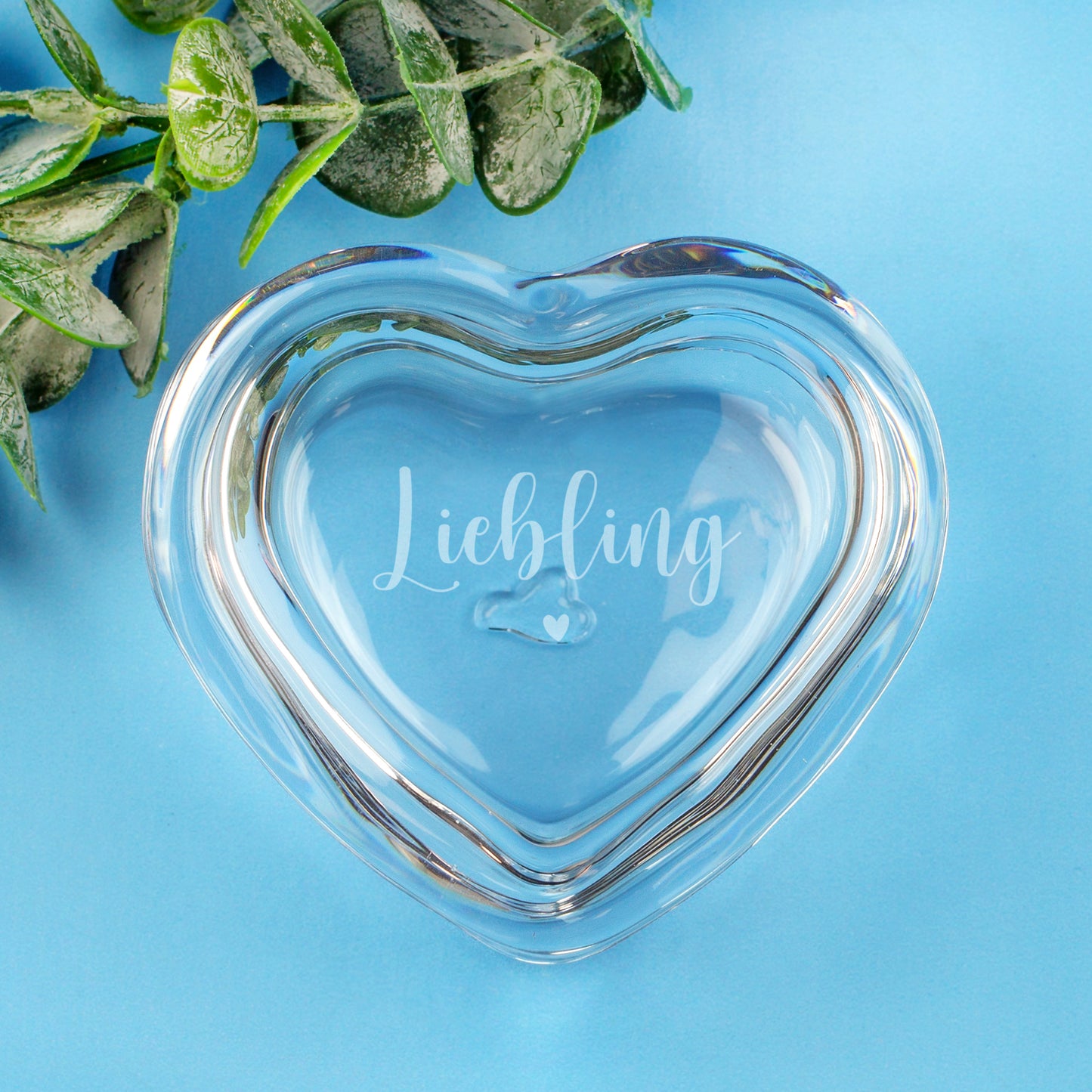 Leonardo Glas-Herzdose mit Gravur Liebling und Herzsymbol auf hellblauem Hintergrund mit Eukalyptus