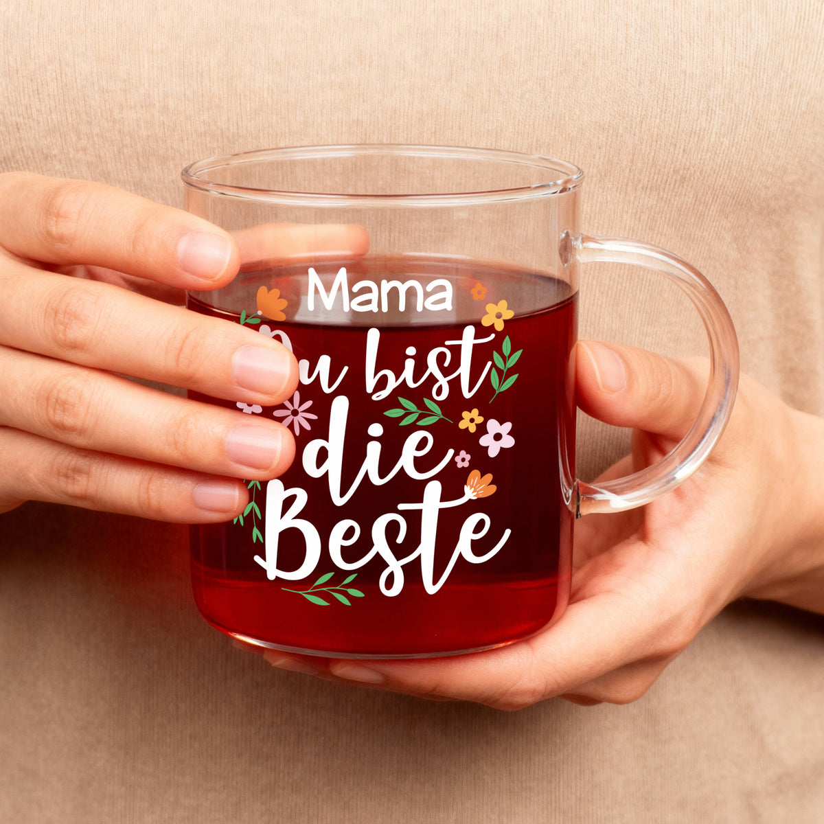 Teeglas mit Aufdruck Mama Du bist die Beste wird in den Händen gehalten als Geschenk zum Muttertag