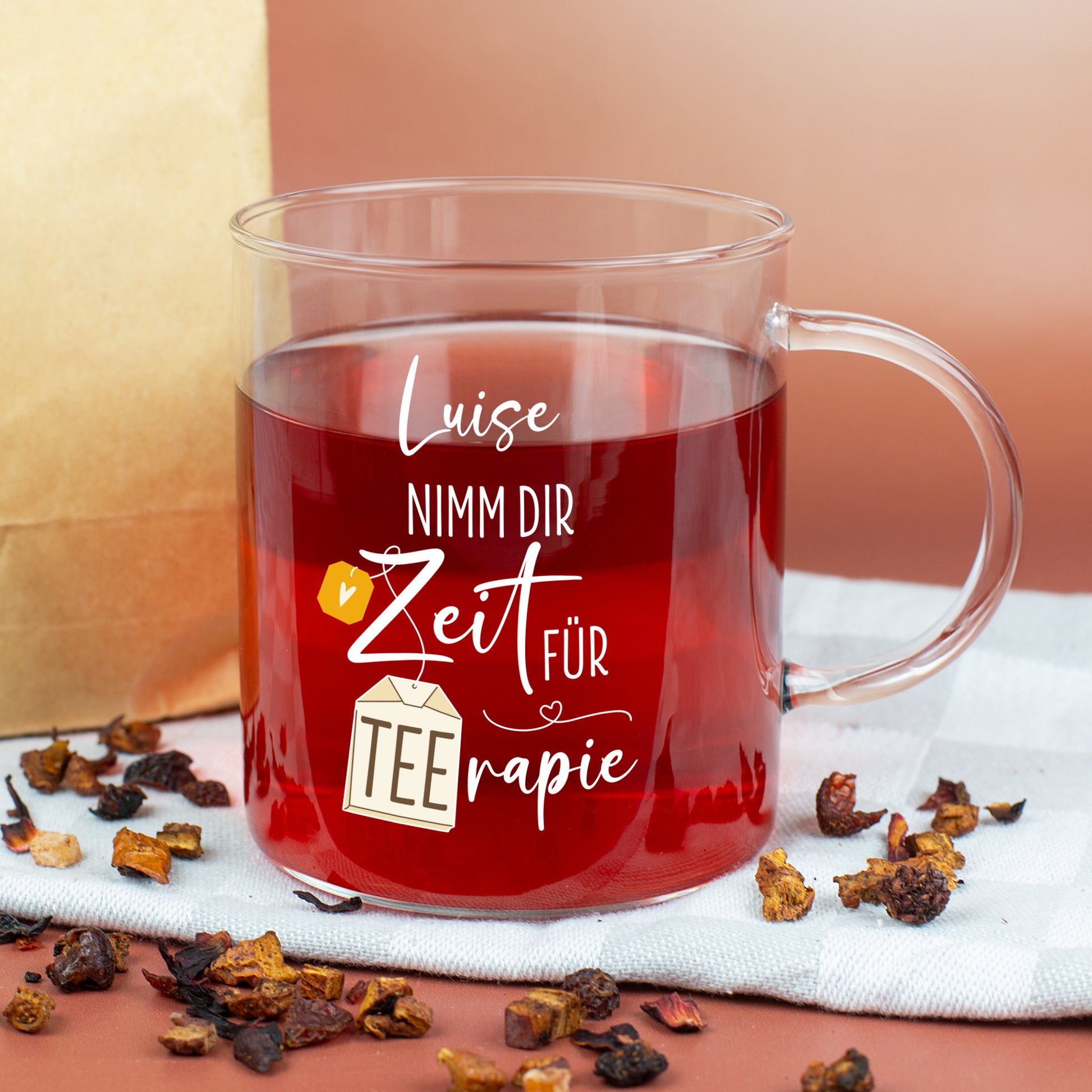 Personalisierbares TEErapie-Teeglas mit Name auf Tisch mit Tee und Früchten