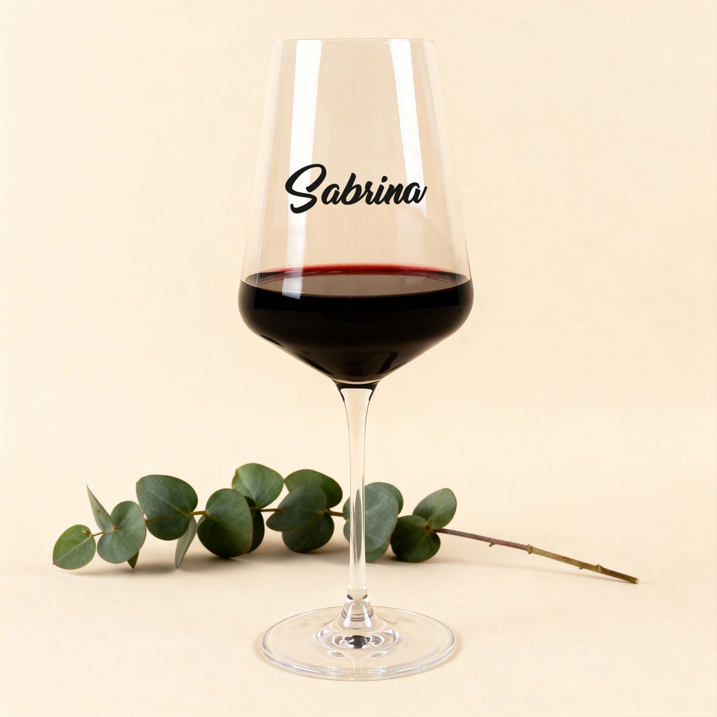 Leonardo Weinglas Puccini mit schwarzem Namensdruck, gefüllt mit Rotwein, vor hellem Hintergrund