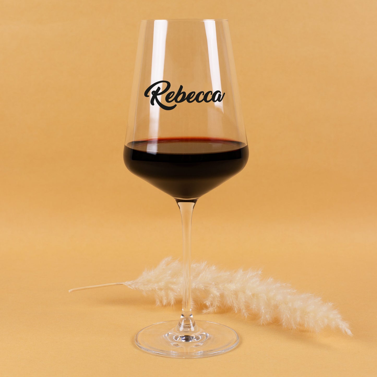 Elegantes Weinglas mit individuellem Namensdruck, gehalten in beiden Händen, warmes Studio-Setting