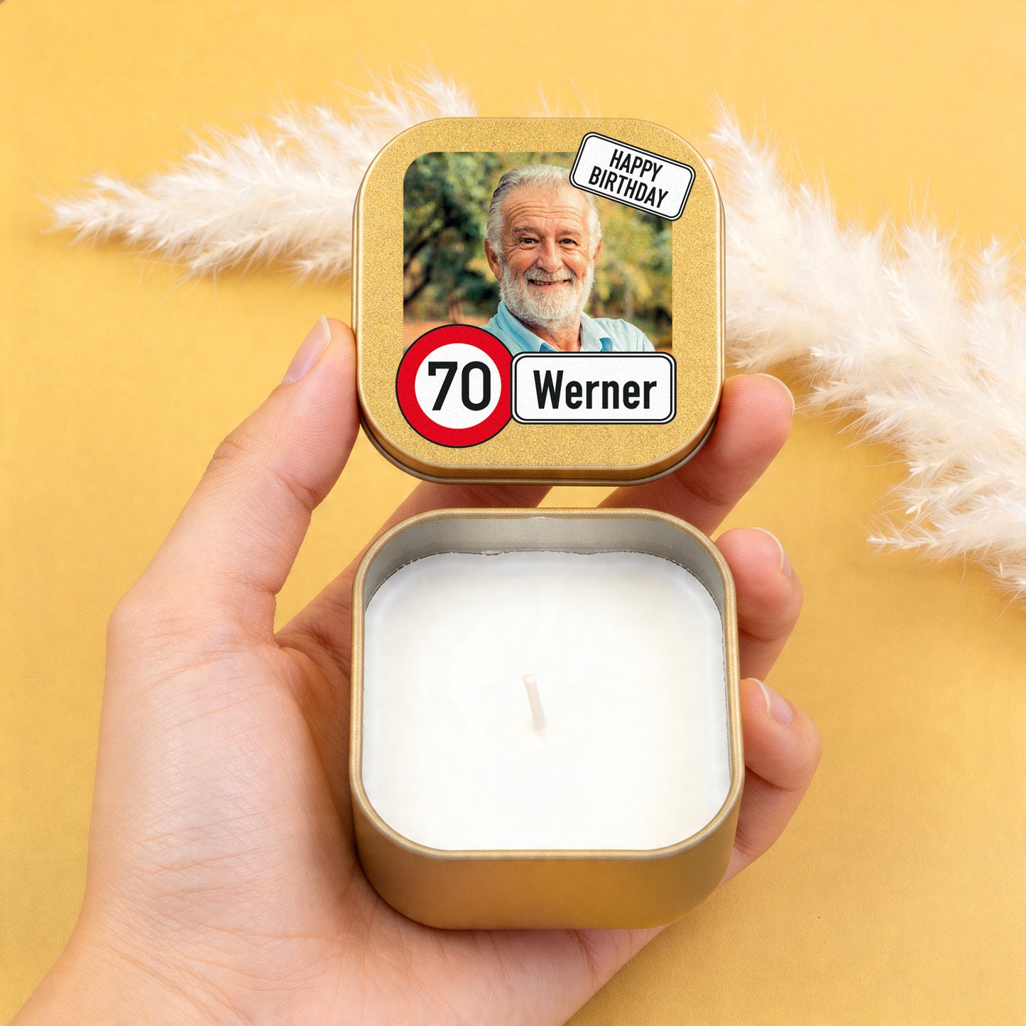 Goldene Mini Duftkerze mit personalisiertem Deckel, Foto, Alter 70 und Name Werner in der Hand auf gelbem Hintergrund