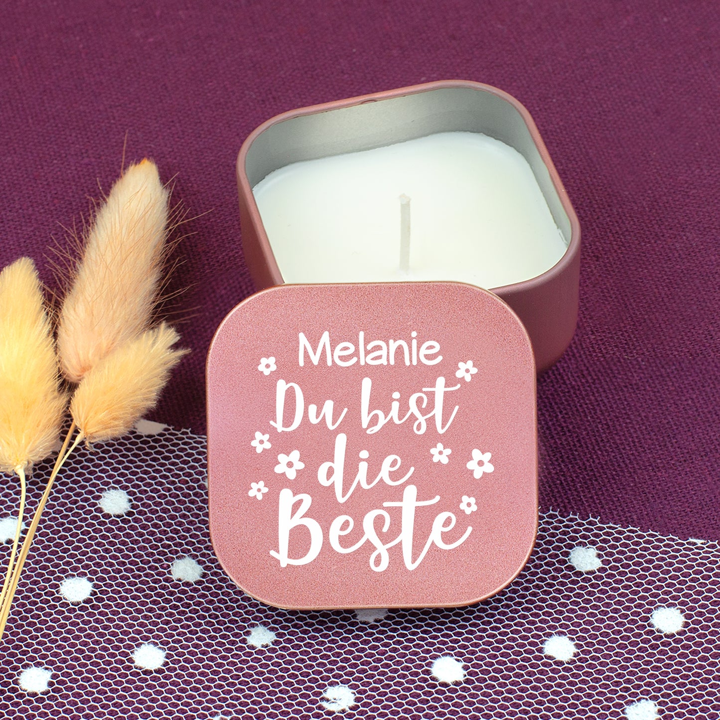 Geöffnete roségoldene Duftkerze mit Vanilleduft, personalisierter Deckel „Melanie Du bist die Beste“ auf violettem Stoff