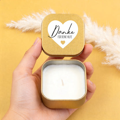 Goldene Duftkerze in einer Hand mit geöffnetem Deckel und Aufschrift Danke für deine Hilfe auf dem Herzmotiv