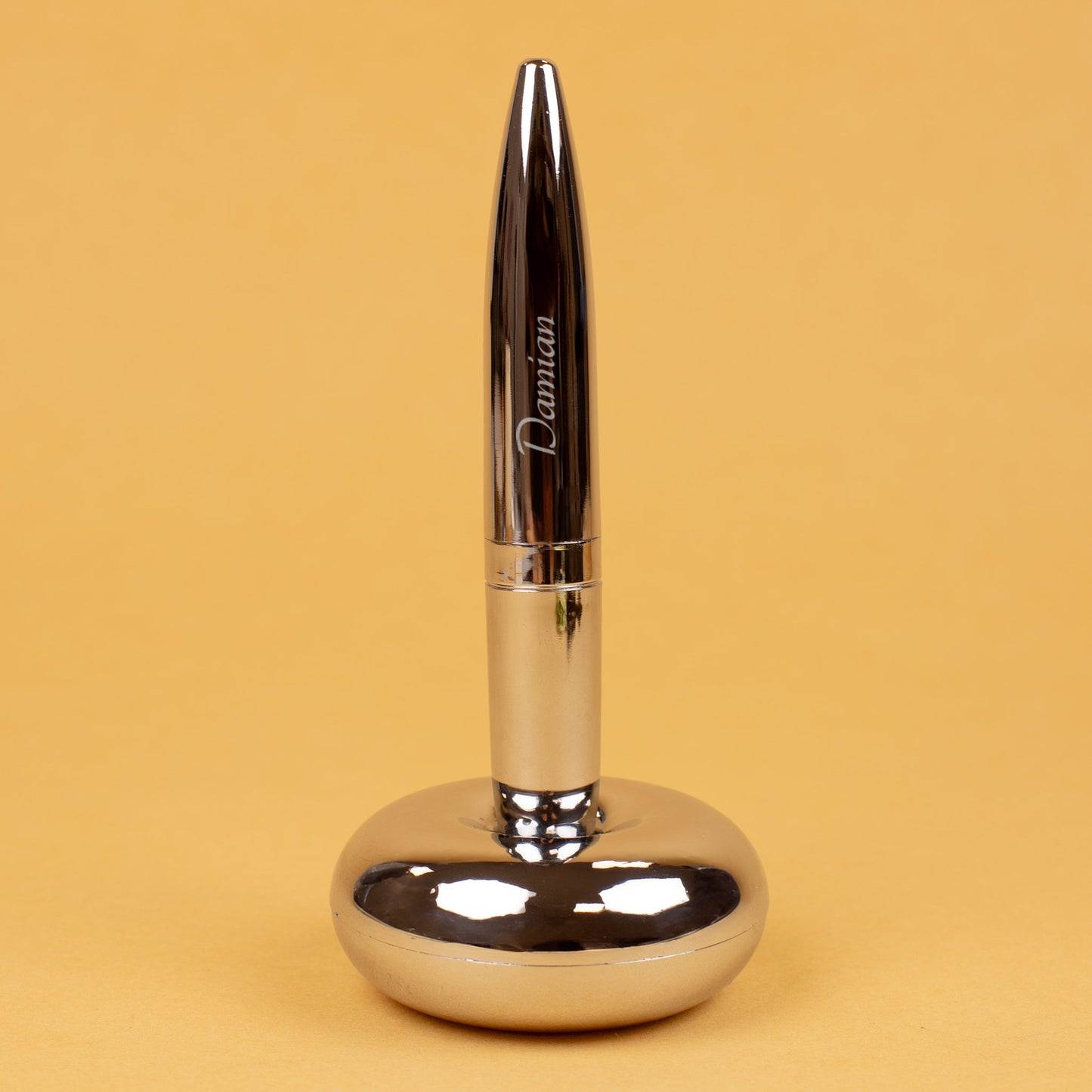 Magischer Kugelschreiber mit Namensgravur stehend in Ständer auf gelbem Hintergrund