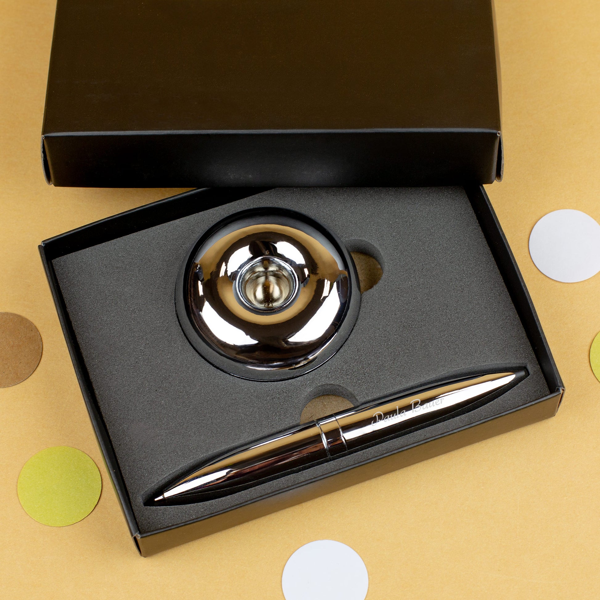 Magischer Kugelschreiber mit Namensgravur liegend mit Ständer in Verpackung auf gelbem Hintergrund