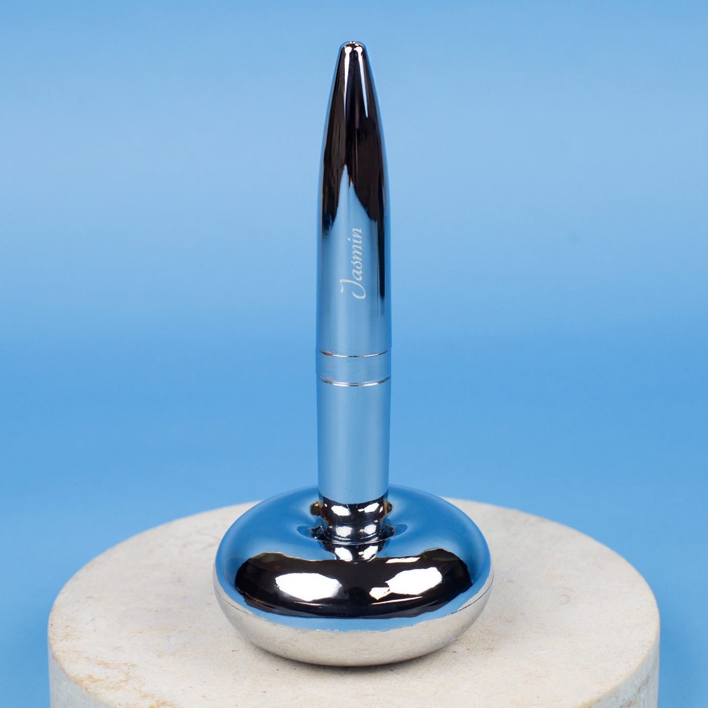 Magischer Kugelschreiber mit Namensgravur stehend in Ständer auf blauem Hintergrund